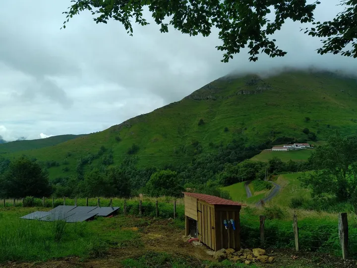 Panneaux au sol et cabanon technique au pied de la montagne