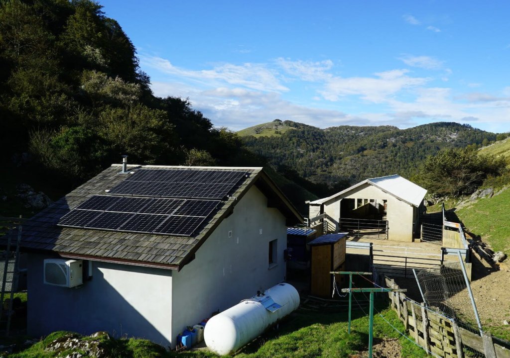 Photo d'une installation de panneaux solaires sur une maison isolée dans la montagne.